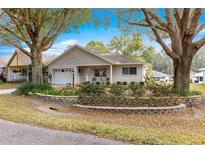 Charming single-story home features a manicured lawn, stone retaining wall, and an attached garage at 9691 Sw 95Th Ct # D, Ocala, FL 34481