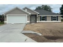 Charming single-story home featuring a two-car garage, well-manicured lawn, and lovely landscaping at 120 Dogwood Drive Cir, Ocala, FL 34472
