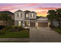 Charming two-story home boasts a two-car garage, complemented by lush landscaping and a vibrant sunset backdrop at 1229 Hillcrest View Loop, Apopka, FL 32703