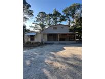 Charming home exterior featuring a large, covered front porch surrounded by mature trees at 9205 Sw 152Nd Pl, Dunnellon, FL 34432