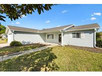 Charming single-story home featuring light blue siding, a well-maintained lawn, and a welcoming walkway to the front door at 10255 Se 178Th Pl, Summerfield, FL 34491