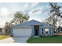 Charming single-story home with blue exterior, stone accents, and a two-car garage at 12164 Se 85Th Ct, Belleview, FL 34420