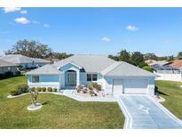 Charming single-story home with a well-manicured lawn and patterned driveway on a sunny day at 17755 Se 117Th Cir, Summerfield, FL 34491