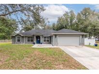 Charming single-story home with a well-manicured lawn, stone accents and a two-car garage at 2045 Marion County Rd, Weirsdale, FL 32195