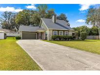 Charming home featuring a stone facade, attached garage and a long driveway on a lush green lawn at 2840 Se 35Th St, Ocala, FL 34471