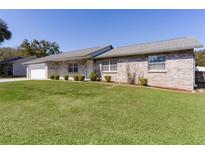 Charming single-story home featuring a well-manicured lawn and a classic brick exterior under a clear blue sky at 3853 Se 60Th St, Ocala, FL 34480