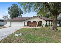 Charming single-story home featuring unique brick accents, arched entryways, mature trees, and an attached two-car garage at 711 Se 26Th St, Ocala, FL 34471