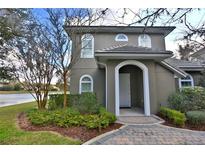 Charming two-story home featuring arched entryway, beautiful landscaping, and serene lake view at 8135 Nw 26Th Lane Rd, Ocala, FL 34482