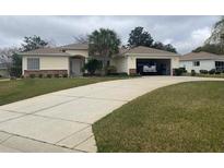 Charming single-story home features a light-yellow exterior, well-manicured lawn and attached garage at 13766 Se 89 Ave, Summerfield, FL 34491