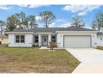 Charming single-story home featuring a well-manicured lawn and a bright white exterior at 14404 Sw 19Th Pl, Ocala, FL 34481