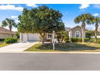 Charming home featuring a two-car garage, mature landscaping, and a well-manicured front lawn at 2310 Nw 59Th Ave, Ocala, FL 34482