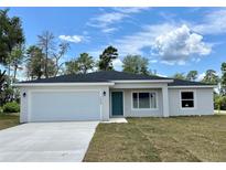 Charming single-story home featuring a two-car garage, a teal front door, and a well-manicured lawn at 269 Marion Oaks Golf Way, Ocala, FL 34473