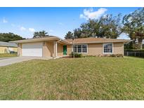 Charming single-story home featuring a well-manicured lawn and a beige color scheme with a two car garage at 4837 Ne 5Th Street Rd, Ocala, FL 34470