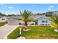 Charming single-story home featuring a well-manicured lawn, beautiful landscaping, and a paver driveway leading to a two-car garage at 9750 Se 179Th Pl, Summerfield, FL 34491