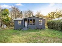 Cozy gray house with a covered front porch and white trim, surrounded by a green lawn and mature trees at 21055 Highway 441 N, Micanopy, FL 32667