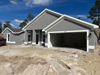 Gray single Gathering home with an attached two car garage and unfinished front yard at 6943 Sw 179Th Court Rd, Dunnellon, FL 34432