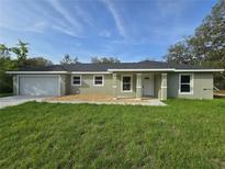 Beautiful home featuring a garage, a cozy front porch, manicured gravel, and a green lawn at 96 Fisher Way Trl, Ocklawaha, FL 32179