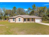 Charming single-story home featuring a well-manicured front lawn, neutral paint, and an attached one-car garage at 13 Pine Course Radl, Ocala, FL 34472