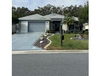 Charming single-story home featuring a well-manicured front yard and a two-car garage at 13340 Se 86Th Cir, Summerfield, FL 34491