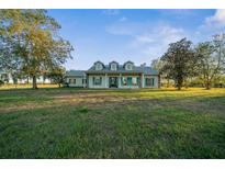 Inviting single-story home featuring a large lawn, symmetrical dormers, and charming turquoise shutters at 6890 Nw 21St St, Ocala, FL 34482