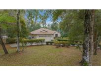 Charming single-story home featuring a well-manicured lawn and mature trees surrounding the property at 7810 Sw 186Th Cir, Dunnellon, FL 34432