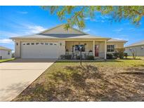 Charming single-story home featuring a cozy front porch and a well-maintained, lush green lawn with a white brick facade at 9866 Sw 97Th Ln, Ocala, FL 34481