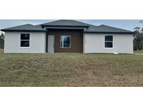 Modern single-story home with a combination of stucco and wood exterior and a well-maintained lawn at 4524 Sw 110Th St, Ocala, FL 34476