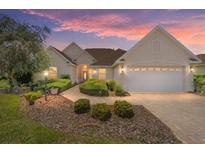 Charming single-story home showcasing manicured landscaping, neutral paint, and a two-car garage during the evening at 8779 Sw 83Rd Cir, Ocala, FL 34481