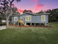 Charming single-story home with blue siding, landscaped yard, and cozy front porch at 11745 Nw 15Th Lane, Ocala, FL 34482