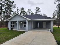 Charming single-story home with a light gray exterior and a covered parking area at 209 Sw Winding Hills Rd, Dunnellon, FL 34431