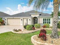 Well-maintained home exterior featuring a three-car garage, a beautiful palm tree, and lush landscaping at 383 Harlow Ln, The Villages, FL 32163