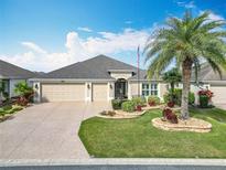Charming single-story home with a well-manicured lawn, mature landscaping, and a three-car garage at 383 Harlow Ln, The Villages, FL 32163