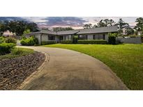 Charming brick home with a well-manicured lawn and a long curved driveway at 4420 Ne 1St St, Ocala, FL 34470