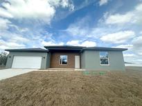 Modern one-story home featuring a gray facade, wood toned accents, and a two-car garage at 4501 Sw 110Th Ln, Ocala, FL 34476