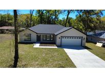 Charming single-story home featuring a two-car garage and a well-maintained front lawn at 6276 Nw 65 Nw Pl, Ocala, FL 34482