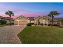 Inviting single-Gathering home with a well-manicured lawn, paver driveway and two-car garage, complemented by palm trees at 9863 Sw 63Rd Loop, Ocala, FL 34481