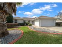 Charming single-story home with manicured lawn, landscaped flower beds, and a two-car garage at 17799 Se 125Th Cir, Summerfield, FL 34491