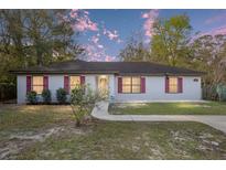 Charming single-story home featuring red shutters, a well-manicured lawn, and a paved walkway at 644 Sw 2Nd St, Ocala, FL 34471