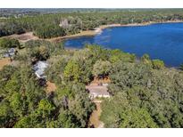 Aerial view of home nestled among trees with lake access, offering a serene and private setting at 17153 Se 79Th Street Rd, Ocklawaha, FL 32179