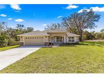 Charming single Gathering home featuring a well-manicured lawn, stone accents, and two-car garage at 20396 Sw 79Th Lane, Dunnellon, FL 34431