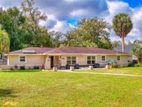 Charming single-story home featuring a well-manicured lawn and inviting front porch with chairs at 3832 Se 2Nd St, Ocala, FL 34471