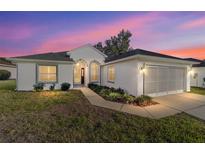 Charming single-story home featuring manicured lawn and a two-car garage, set against a vibrant twilight sky at 11569 Sw 71St Cir, Ocala, FL 34476