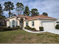 Charming single-story home with manicured lawn and a two-car garage with a brown roof at 11663 Sw 72Nd Cir, Ocala, FL 34476