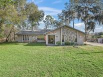 Charming single-story home featuring stone accents and a lush green lawn surrounded by mature trees at 16211 Se 62Nd Pl, Ocklawaha, FL 32179