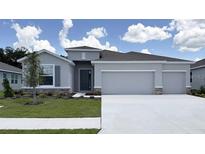 Charming single-story home featuring a two car garage, neutral paint, stone accents and a well manicured lawn at 3071 Canopy Oak Blvd, Wildwood, FL 34785