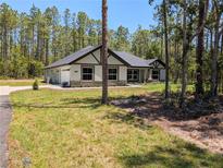 Well-maintained home with lush lawn, stone accents, and a two-car garage at 8303 Sw 127 Ave, Dunnellon, FL 34432