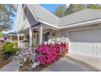 Charming home featuring a well-manicured yard with vibrant azaleas and a welcoming front porch at 8475 Sw 91St Pl # E, Ocala, FL 34481