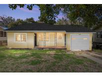 Charming yellow home featuring a welcoming front porch, well-kept lawn, and an attached garage at 903 Ne 2Nd St, Ocala, FL 34470