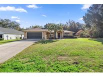 Charming single-story home with a well-manicured lawn and a two-car garage at 14059 Sw 47Th Ave, Ocala, FL 34473