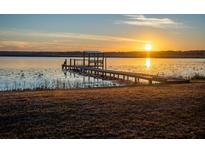 Waterfront view featuring a dock with seating during a colorful sunset overlooking a serene lake at 14540 Ne 250Th Ave, Fort Mc Coy, FL 32134